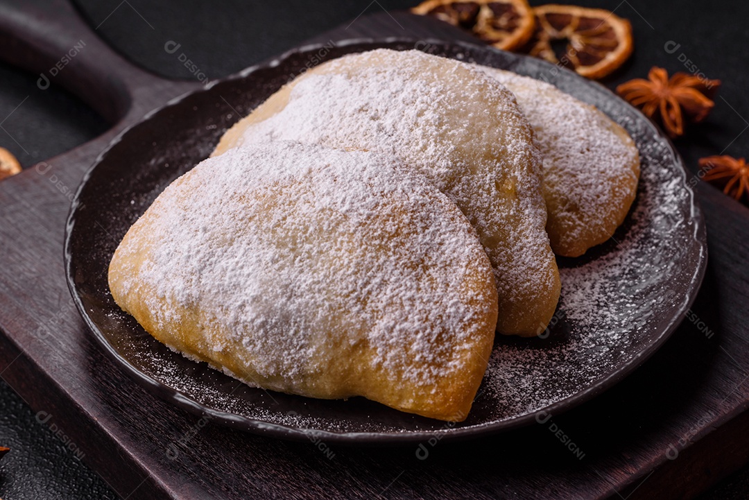 A imagem mostra biscoitos ou pastéis polvilhados com açúcar de confeiteiro, que podem ser semelhantes ao pastel de carne com açúcar