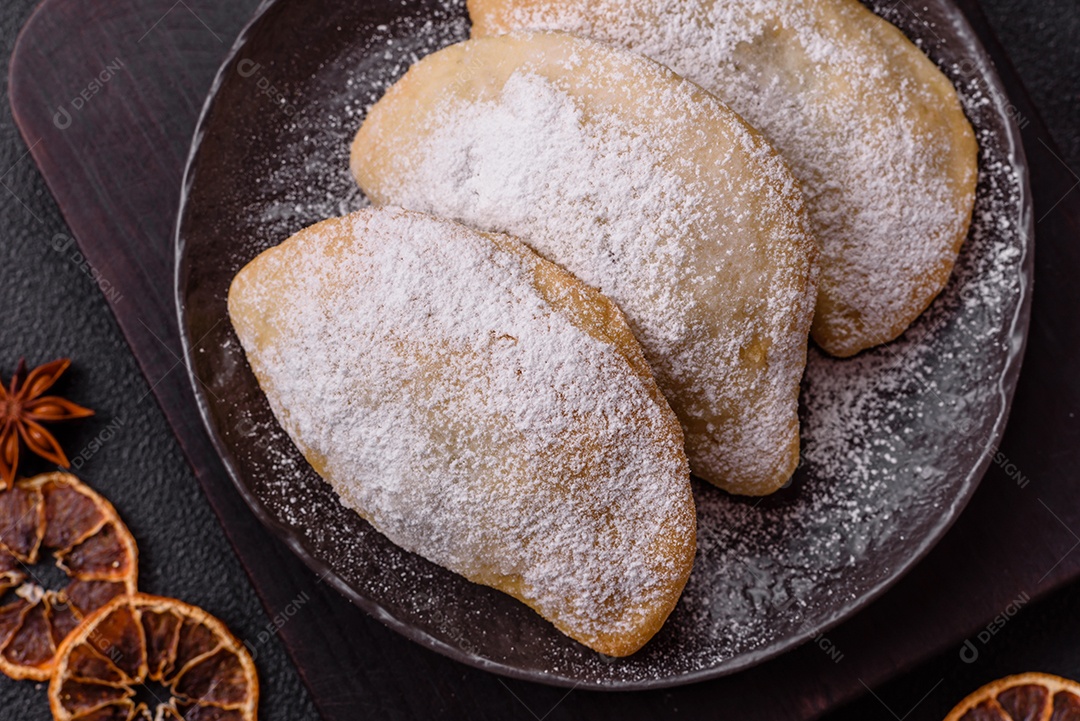 A imagem mostra biscoitos ou pastéis polvilhados com açúcar de confeiteiro, que podem ser semelhantes ao pastel de carne com açúcar