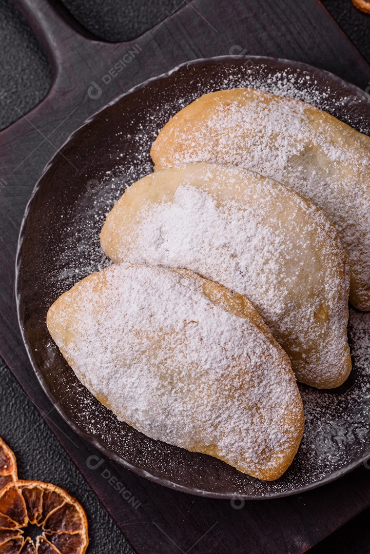 A imagem mostra biscoitos ou pastéis polvilhados com açúcar de confeiteiro, que podem ser semelhantes ao pastel de carne com açúcar