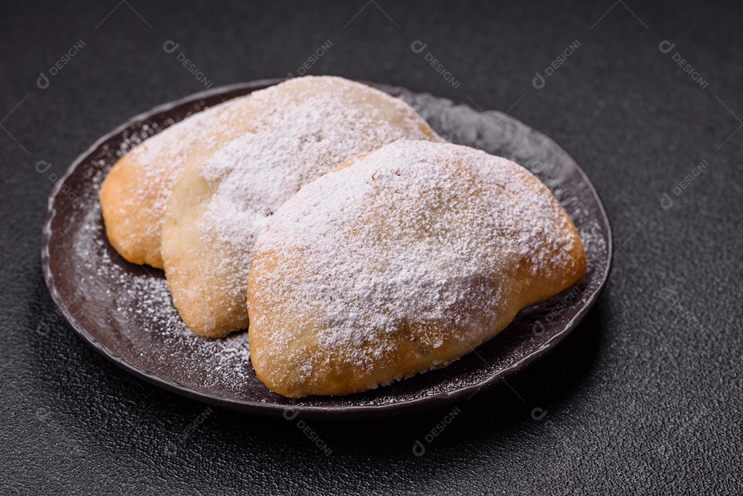 A imagem mostra biscoitos ou pastéis polvilhados com açúcar de confeiteiro, que podem ser semelhantes ao pastel de carne com açúcar