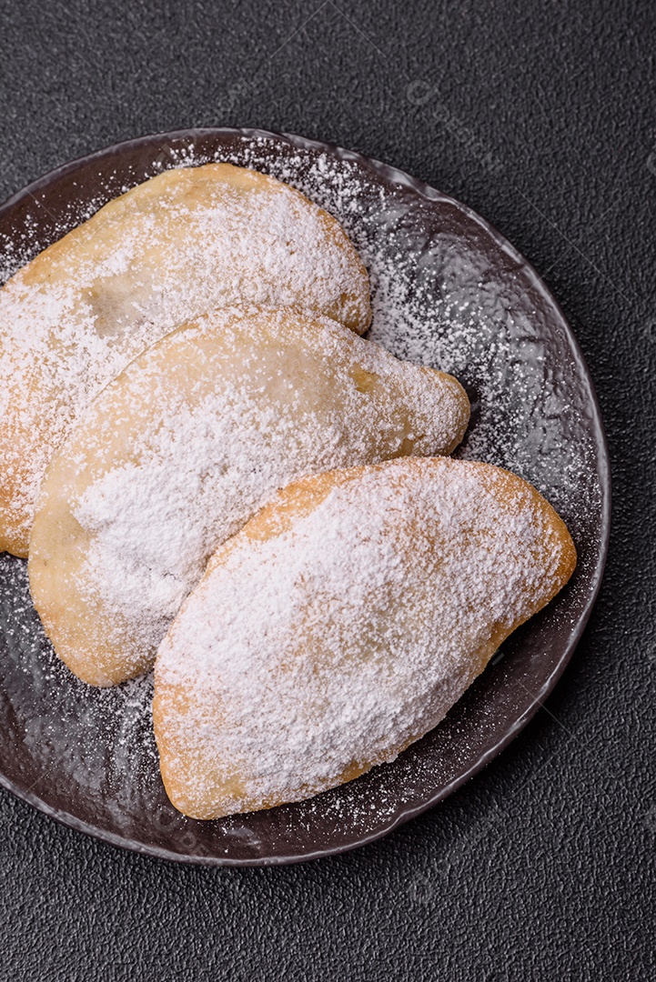A imagem mostra biscoitos ou pastéis polvilhados com açúcar de confeiteiro, que podem ser semelhantes ao pastel de carne com açúcar