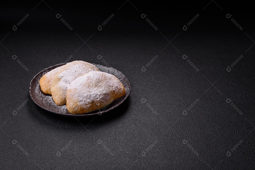 A imagem mostra biscoitos ou pastéis polvilhados com açúcar de confeiteiro, que podem ser semelhantes ao pastel de carne com açúcar