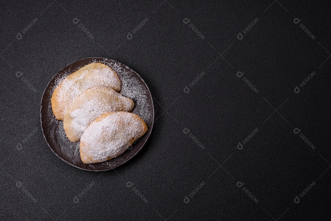 A imagem mostra biscoitos ou pastéis polvilhados com açúcar de confeiteiro, que podem ser semelhantes ao pastel de carne com açúcar