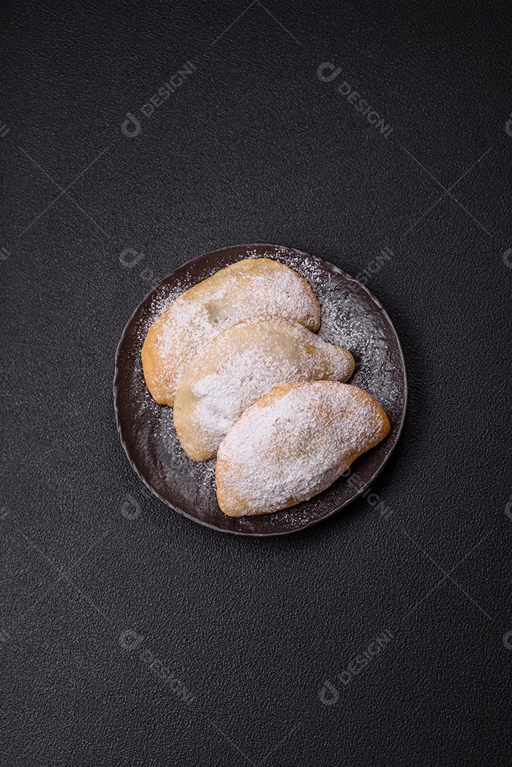A imagem mostra biscoitos ou pastéis polvilhados com açúcar de confeiteiro, que podem ser semelhantes ao pastel de carne com açúcar