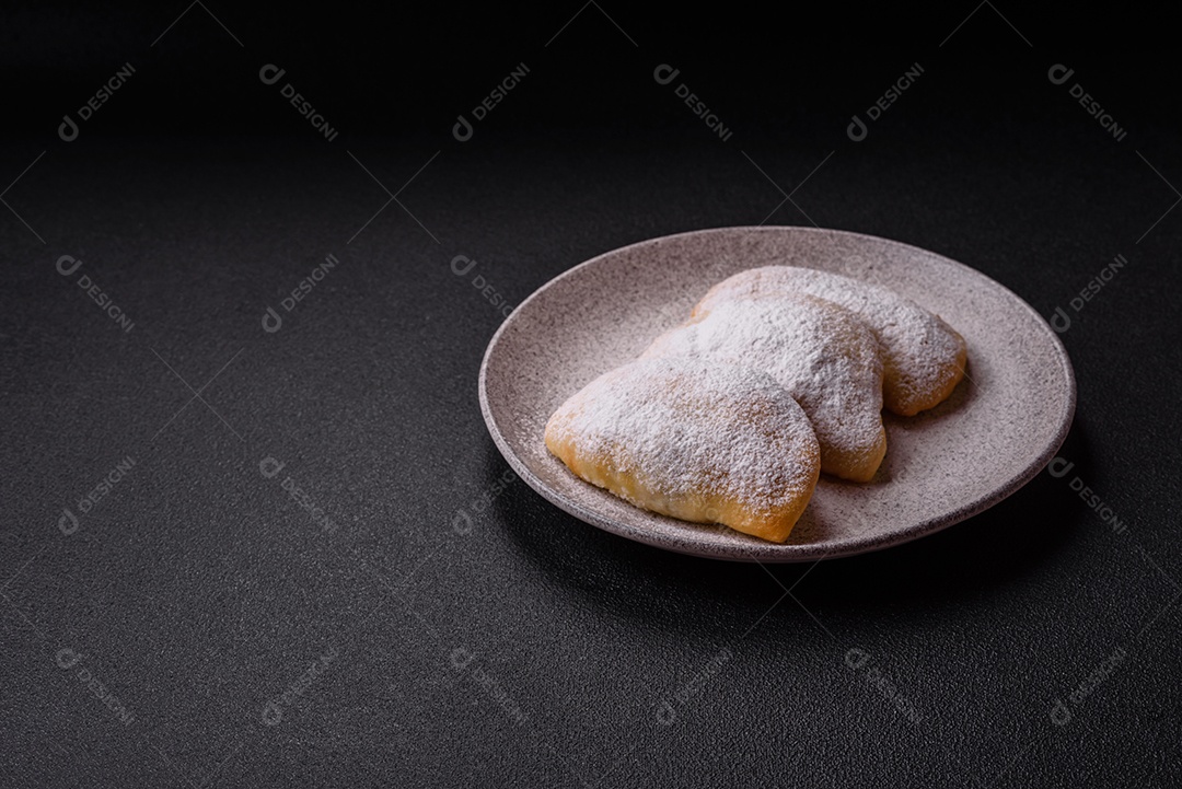A imagem mostra biscoitos ou pastéis polvilhados com açúcar de confeiteiro, que podem ser semelhantes ao pastel de carne com açúcar