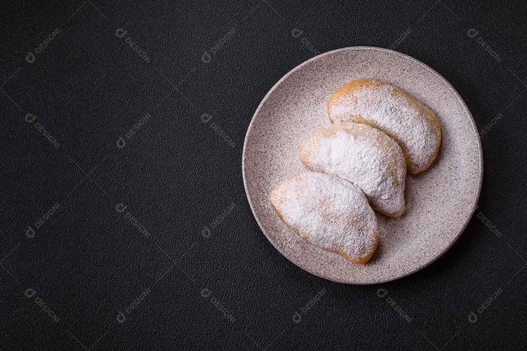 A imagem mostra biscoitos ou pastéis polvilhados com açúcar de confeiteiro, que podem ser semelhantes ao pastel de carne com açúcar