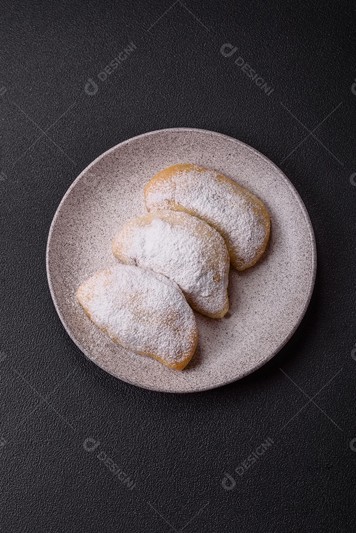 A imagem mostra biscoitos ou pastéis polvilhados com açúcar de confeiteiro, que podem ser semelhantes ao pastel de carne com açúcar