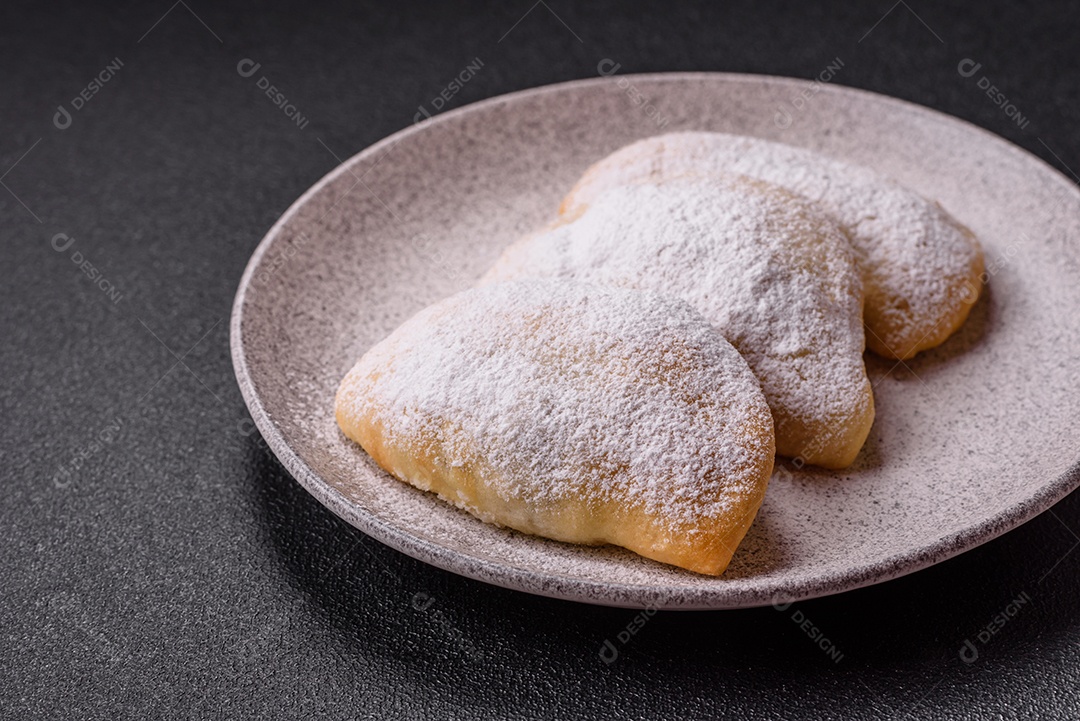 A imagem mostra biscoitos ou pastéis polvilhados com açúcar de confeiteiro, que podem ser semelhantes ao pastel de carne com açúcar