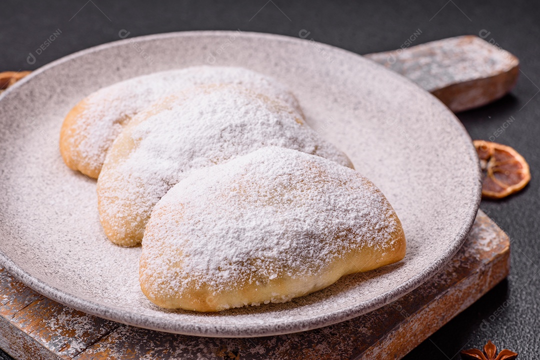 A imagem mostra biscoitos ou pastéis polvilhados com açúcar de confeiteiro, que podem ser semelhantes ao pastel de carne com açúcar