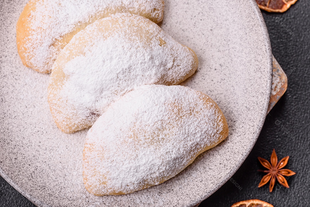 A imagem mostra biscoitos ou pastéis polvilhados com açúcar de confeiteiro, que podem ser semelhantes ao pastel de carne com açúcar