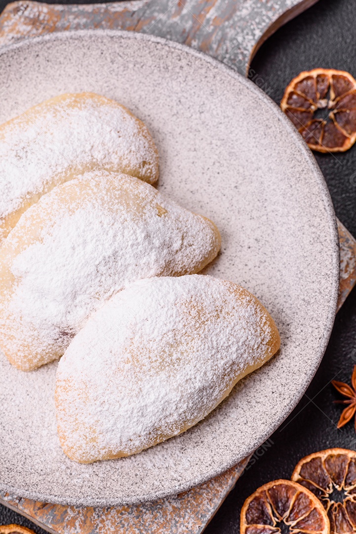 A imagem mostra biscoitos ou pastéis polvilhados com açúcar de confeiteiro, que podem ser semelhantes ao pastel de carne com açúcar