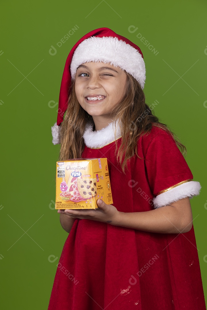Linda garotinha feliz usando gorro do papai noel segurando Panetone